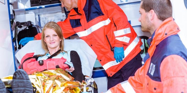 Une femme avec le bras cassé est évacué par des ambulanciers en portant une attelle à dépression