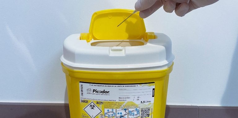soignant jetant une aiguille dans un conteneur DASRI