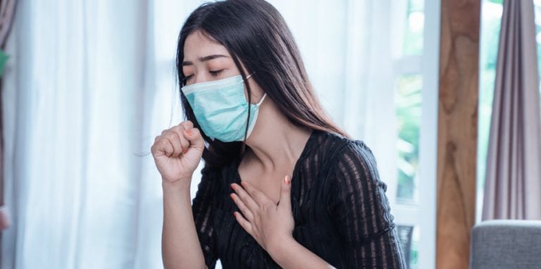femme avec un masque présentant des symptômes du Covid