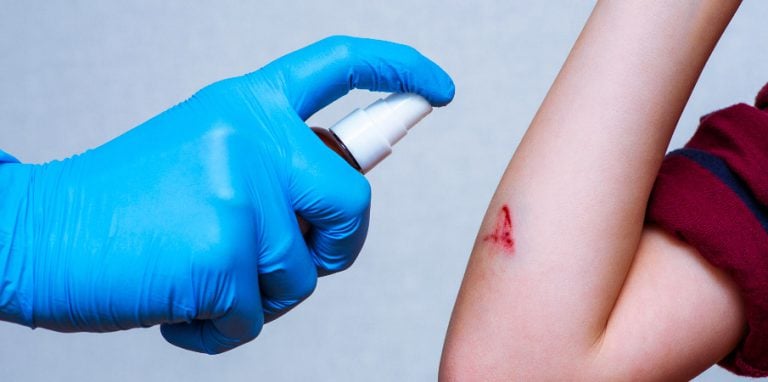 soignant en train d'appliquer un desinfectant antiseptique sur un enfant
