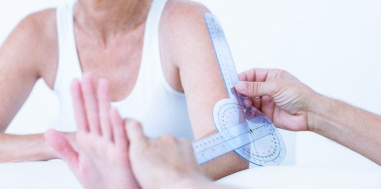 médecin mesure l'angle du coude d'une patiente à l'aide d'un goniomètre