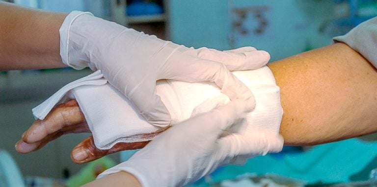 infirmière soignant une plaie exsudative avec un pansement compressif