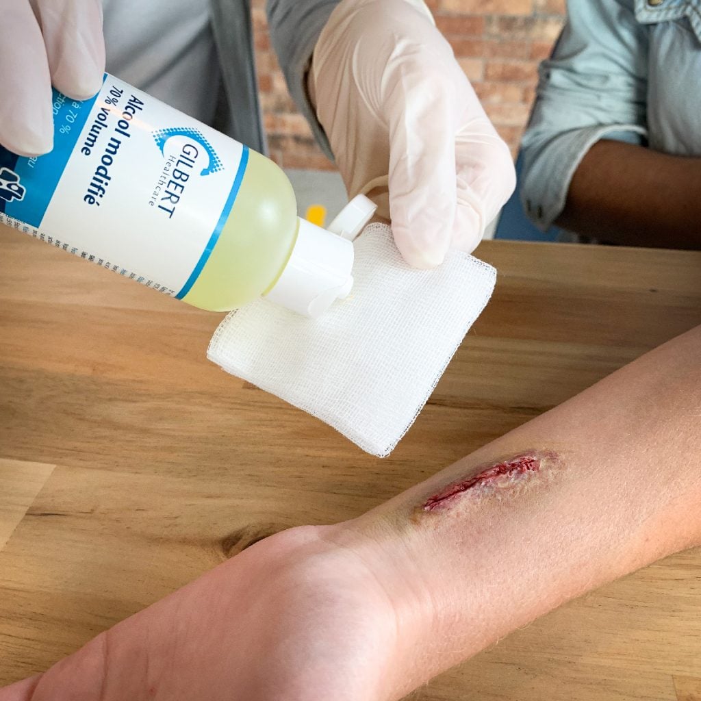 infirmière versant de l'alcool 70° sur une compresse de gaze stérile