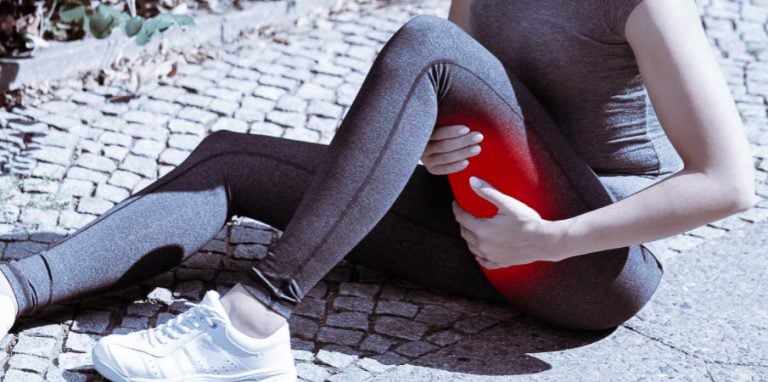 Femme faisant du sport et qui a une crampe musculaire à la cuisse