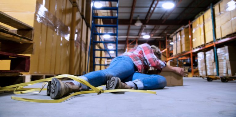 Photo d'un employé tombé dans un entrepôt après s'être pris les pieds dans un ruban de carton